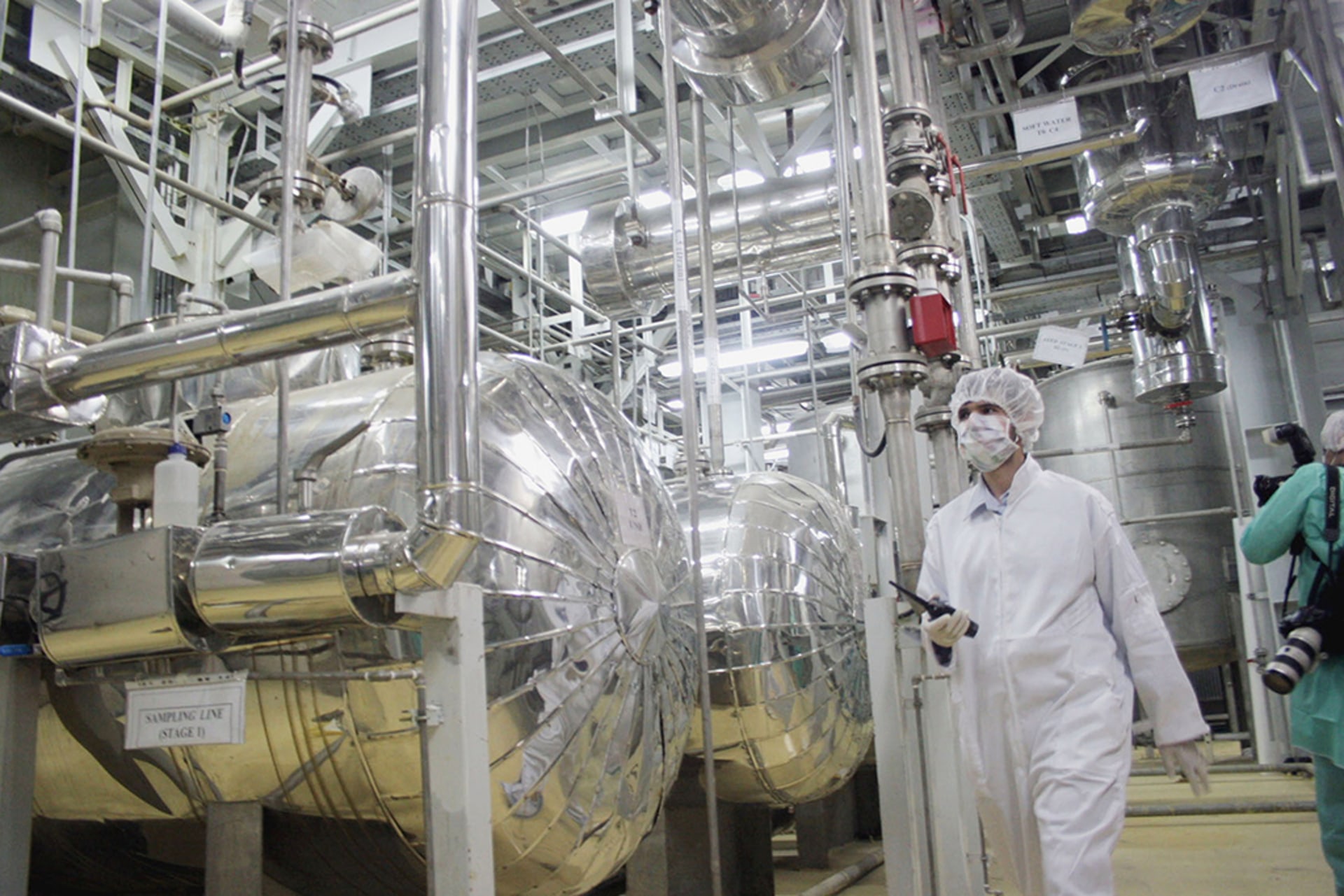 A worker in protective gear walks inside of an uranium conversion facility,