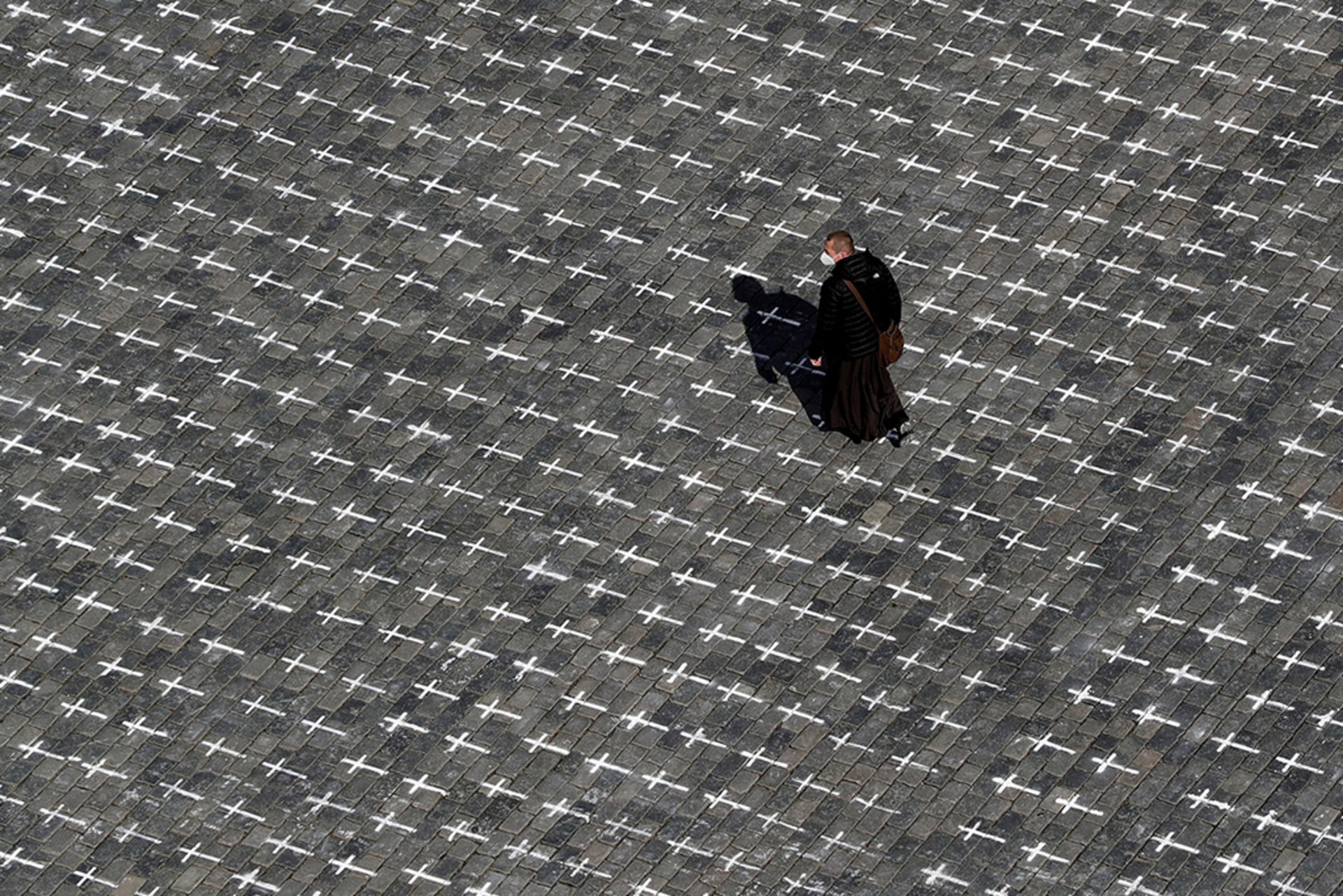 A man walks across the Old Town Square where thousands of crosses have been painted on a pavement to commemorate the first anniversary since the death of the first Czech coronavirus disease (COVID-19) patient in Prague, Czech Republic.