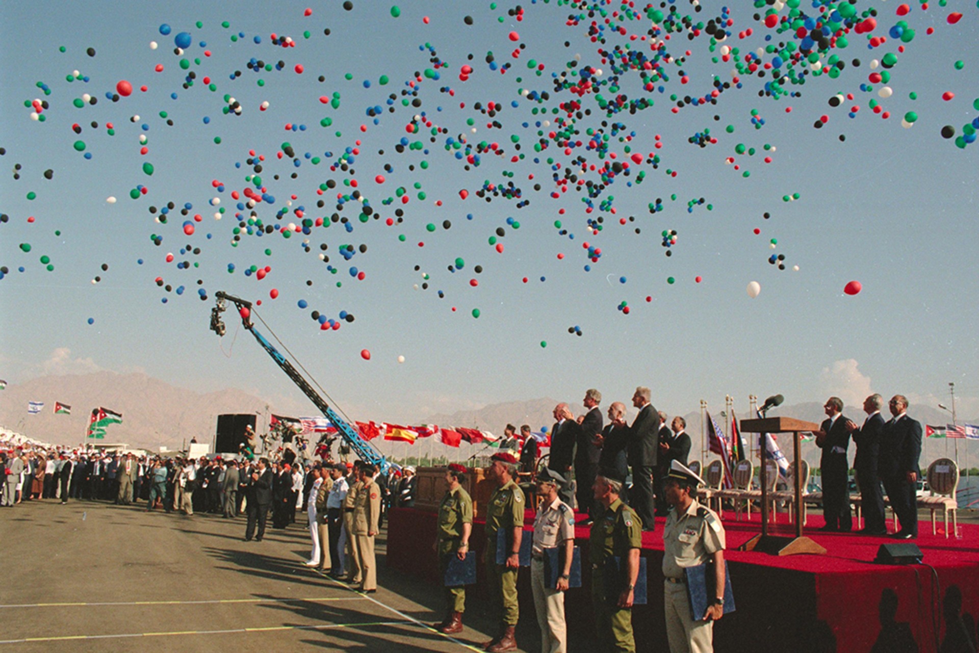 Hundreds of thematic balloons the color of the Israeli and Palestinian flags are released into the air during the Israel-Jordan peace treaty signing ceremony at the Arava Terminal. The leaders look up to the sky at the spectacle.