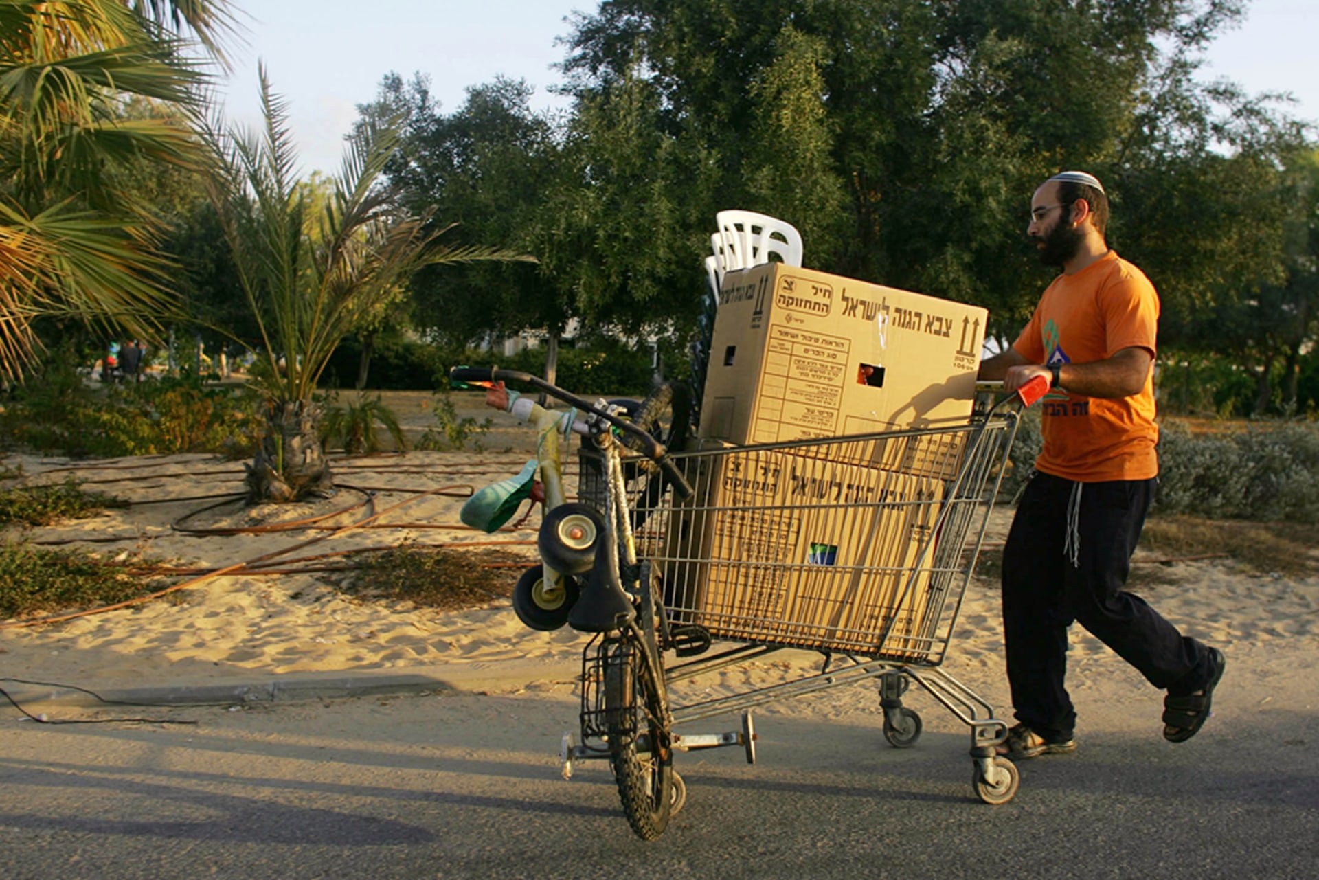 A Jewish settler carts away his belongings before Israeli soldiers arrived to evacuate the Jewish settlement of Katif. Using an old shopping cart the settler transports a large cardboard box and bicycle.