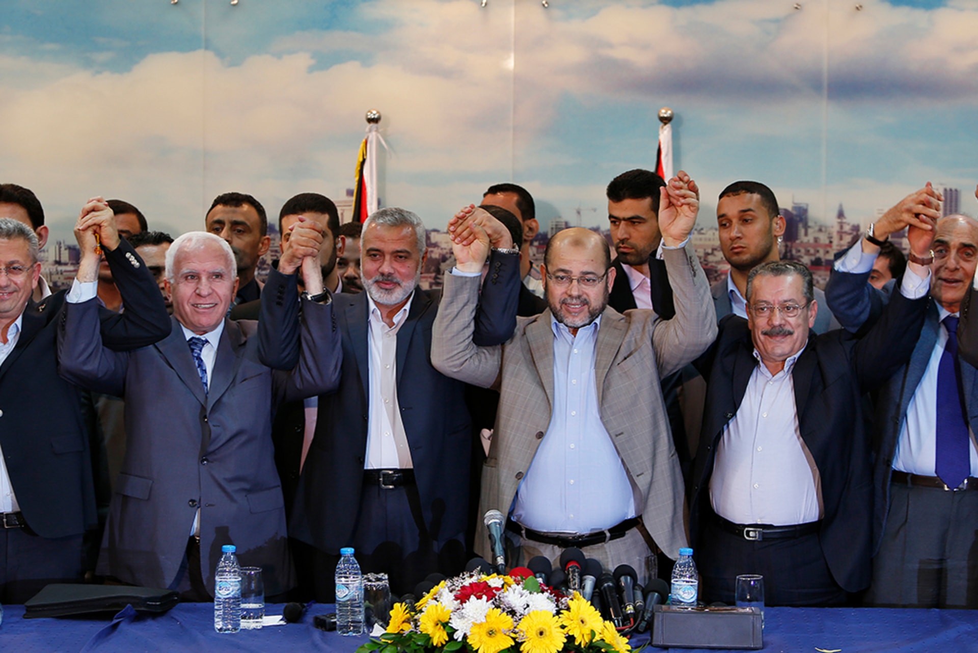 Senior Fatah official Azzam Al-Ahmed, head of the Hamas government Ismail Haniyeh, and senior Hamas leader Moussa Abu Marzouq stand side by side and raise their held hands in the air after announcing a reconciliation agreement in Gaza City.