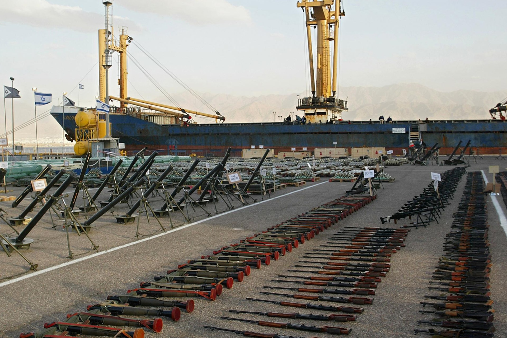Lots of weapons and explosives are laid out on a port next to the cargo ship Karmine A.