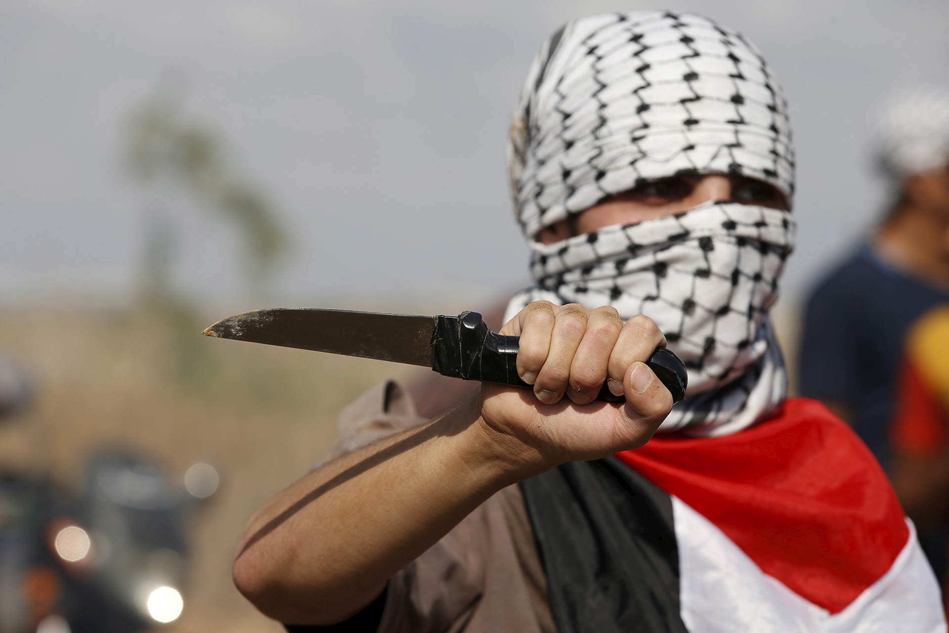 A masked Palestinian protester holds a knife during a protest.