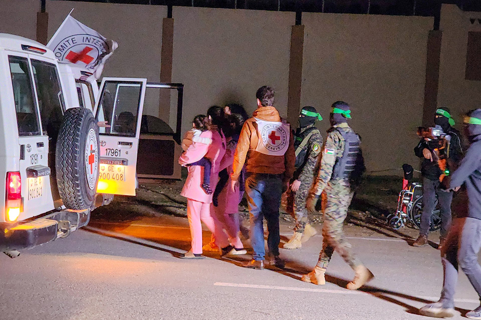 Hostages are led to an International Committee of the Red Cross van by masked Hamas members.