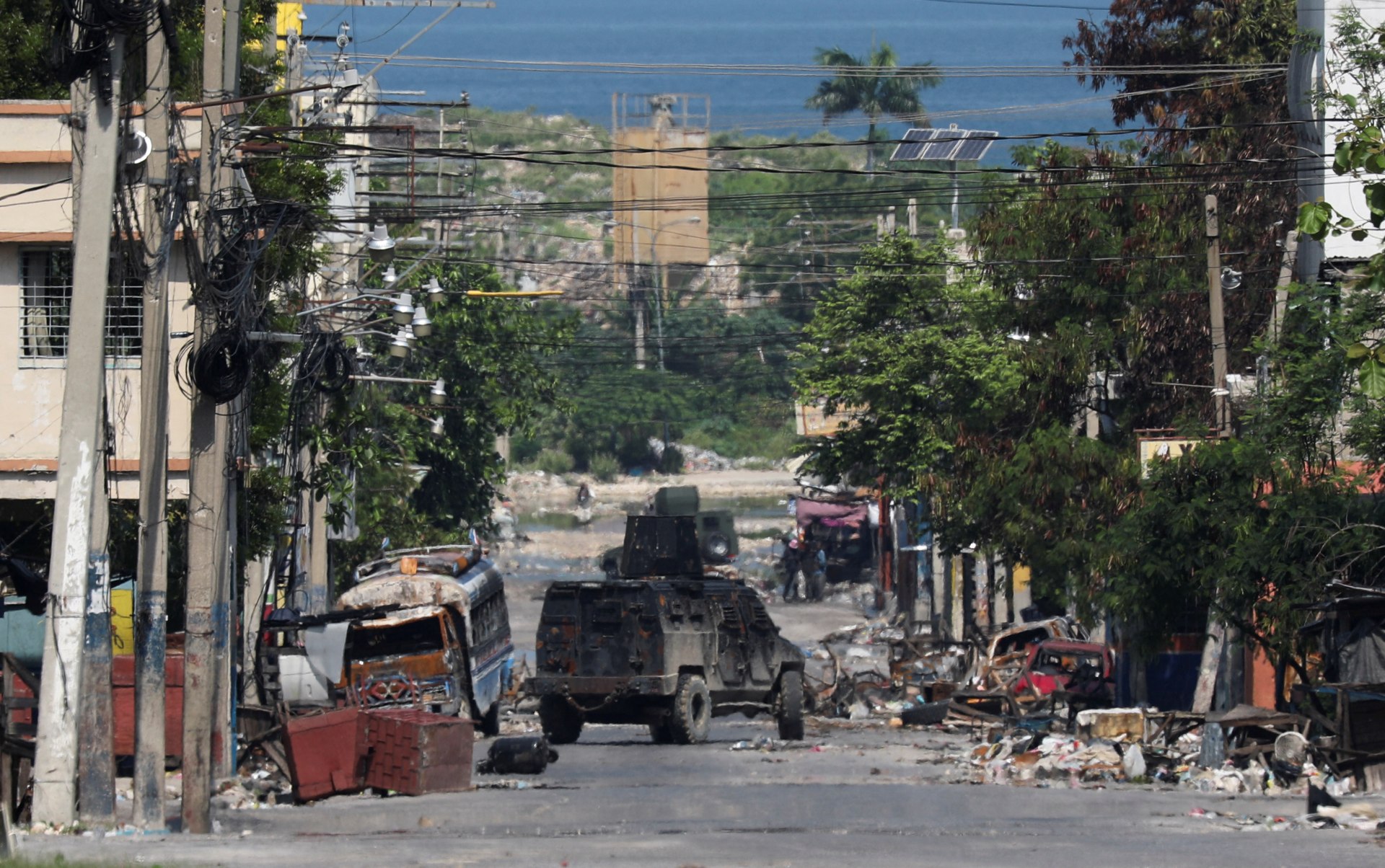 A photo of a street in Haiti with an armored vehicle and debris