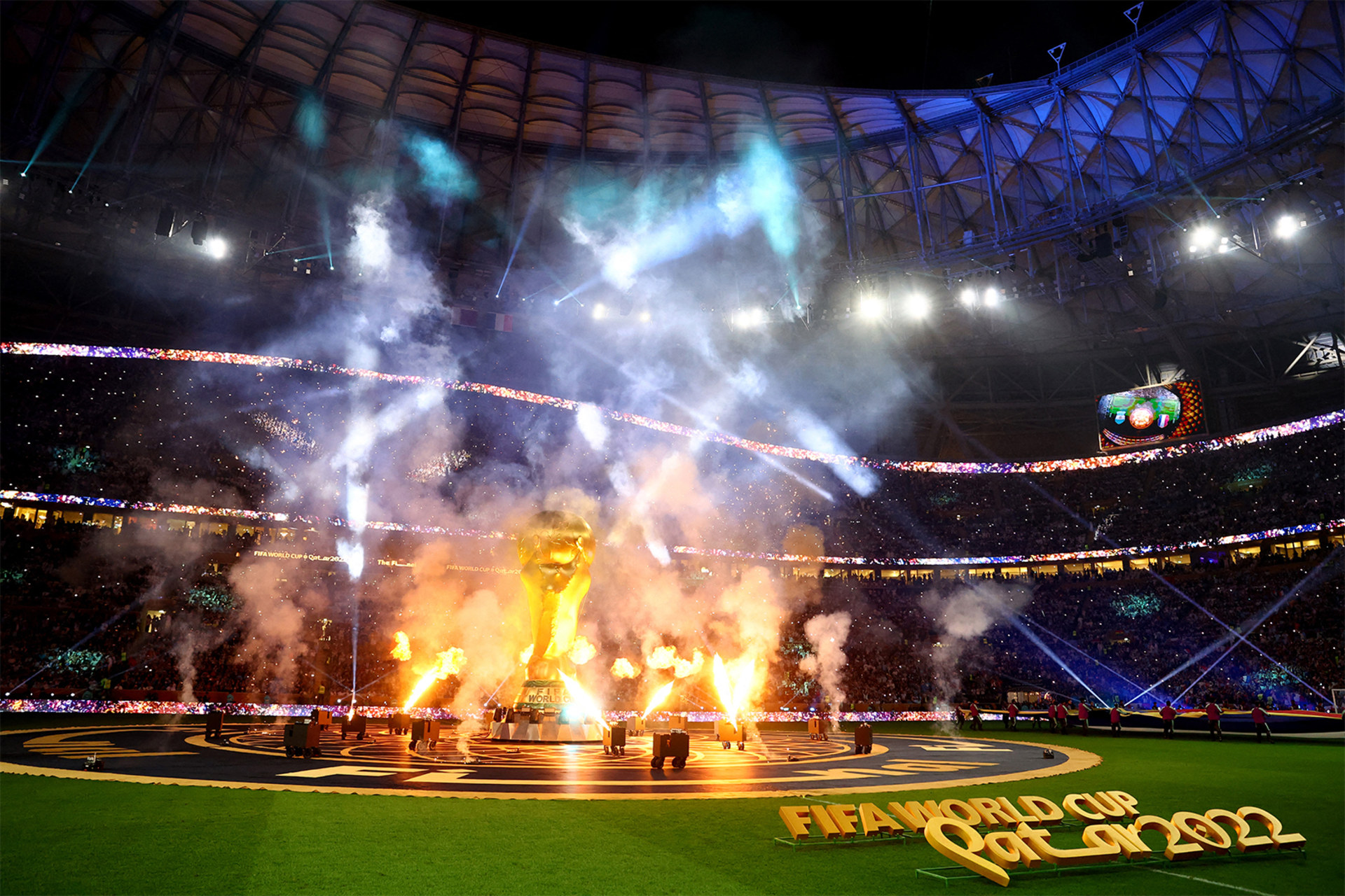 The FIFA World Cup 2022 closing ceremony held in Lusail Stadium, Lusail, Qatar can be seen as a giant FIFA trophy stands in the center and celebratory flames surround it.