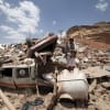 A Houthi militant stands amidst debris from a house.