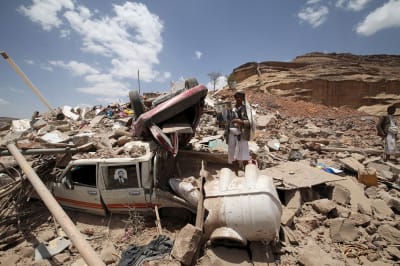 A Houthi militant stands amidst debris from a house.