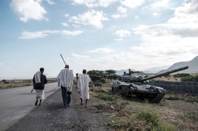 Men son road next to tank.