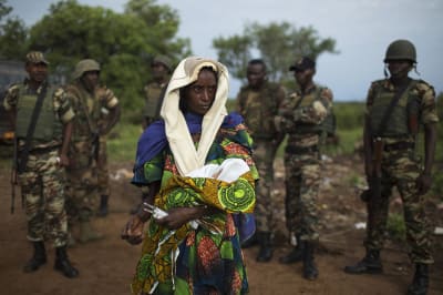 Woman holding baby escorted by African Union troops.