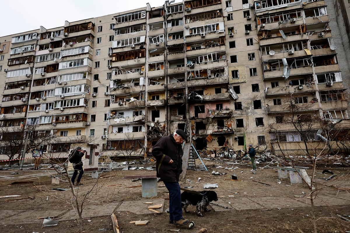 A person walks his dog in front of a damaged residential building, after Russia launched a massive military operation against Ukraine, in Kyiv, Ukraine on February 25, 2022. 