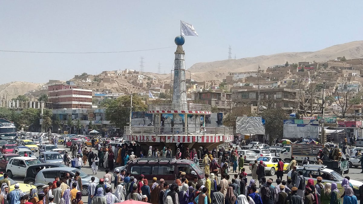 A Taliban flag is seen on a plinth with people gathered around the main city square at Pul-e-Khumri on August 11, 2021 after Taliban captured Pul-e-Khumri.