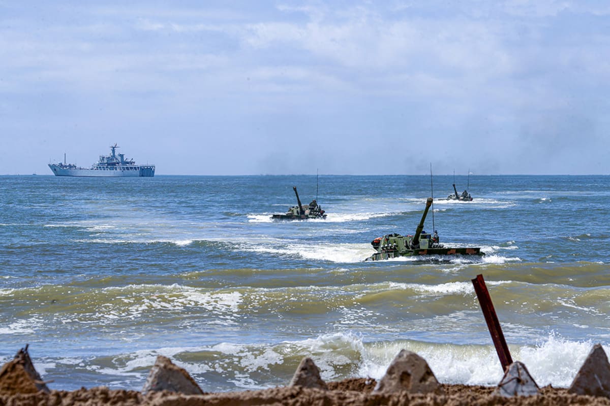Amphibious vehicles land on beach.