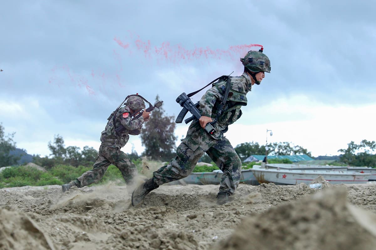 Two soldiers run through sand.