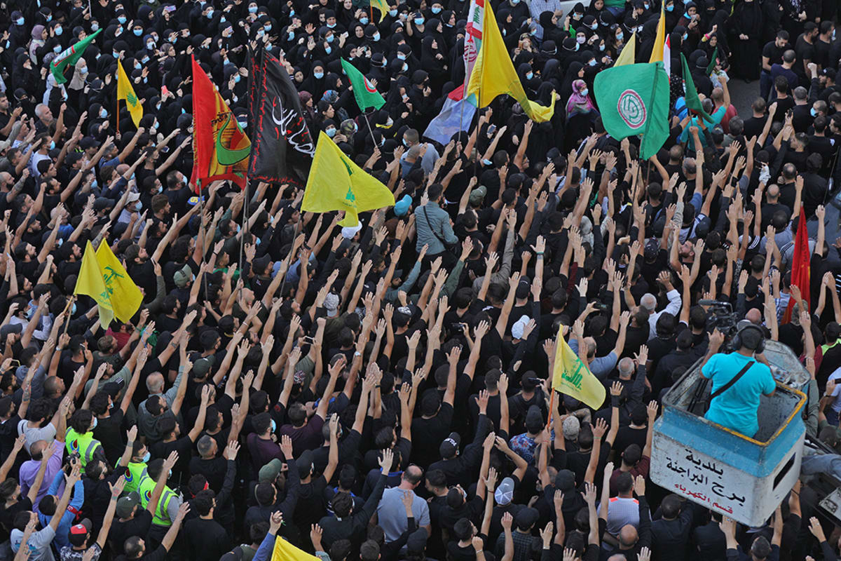 A crowd of people marches carrying yellow flags.