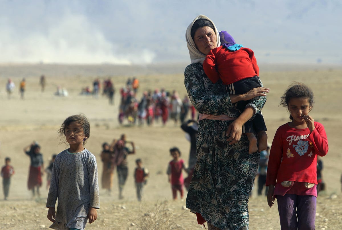 Displaced people from the minority Yazidi sect, fleeing violence from forces loyal to the Islamic State in Sinjar town, walk towards the Syrian border on August 11, 2014. 