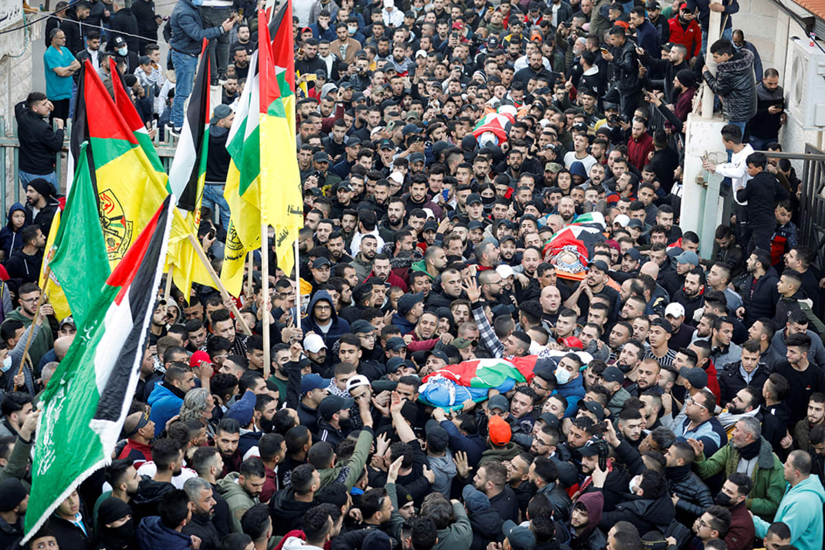 Mourners carry the bodies of three Palestinians killed by Israeli forces during a funeral in Nablus, on February 8, 2022.