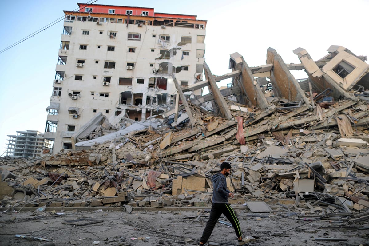 A Palestinian boy walks past the remains of a tower building destroyed in Israeli airstrikes in Gaza City, on May 12, 2021.