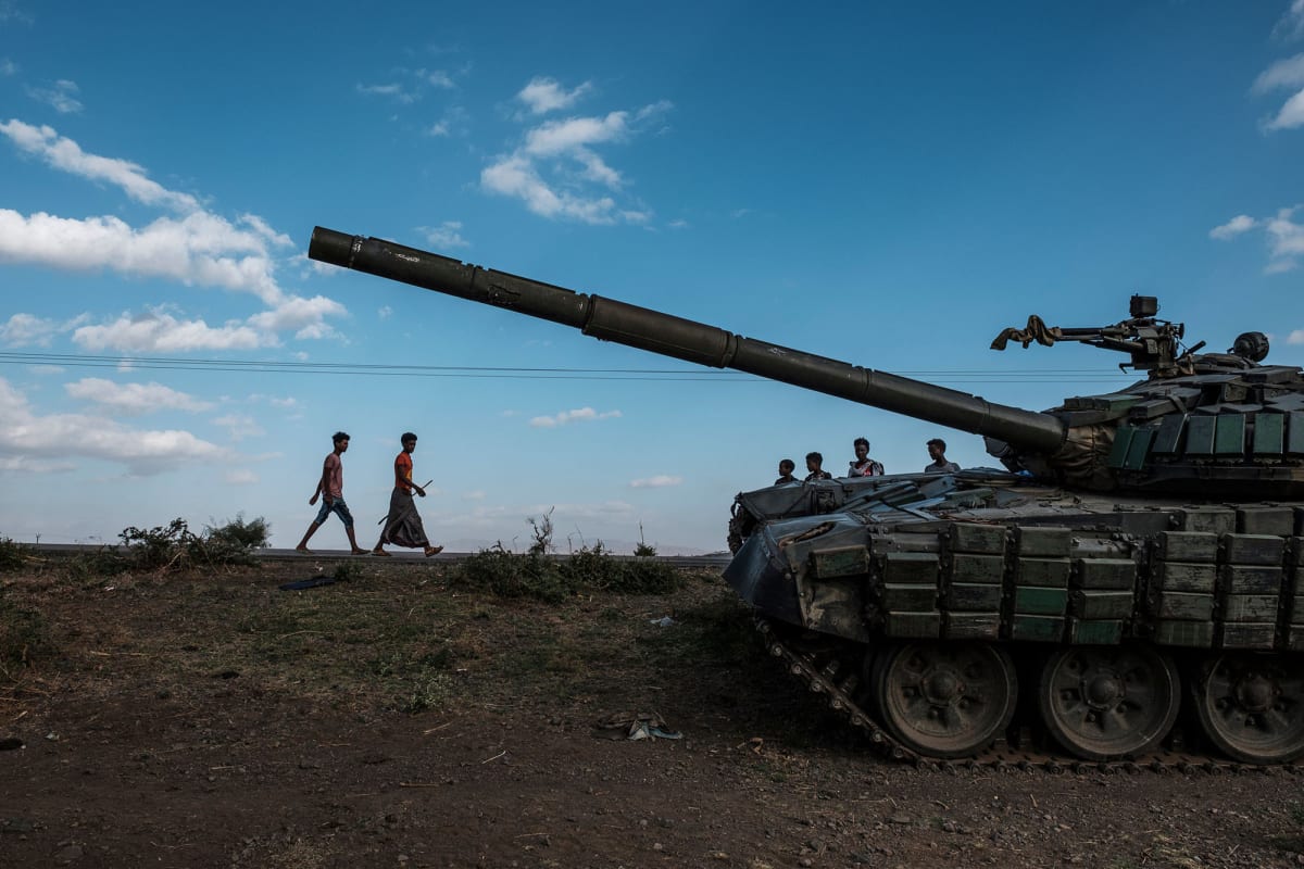 Youngsters walk next to an abandoned tank belonging to Tigrayan forces south of the town of Mehoni, Ethiopia, on December 11, 2020. 