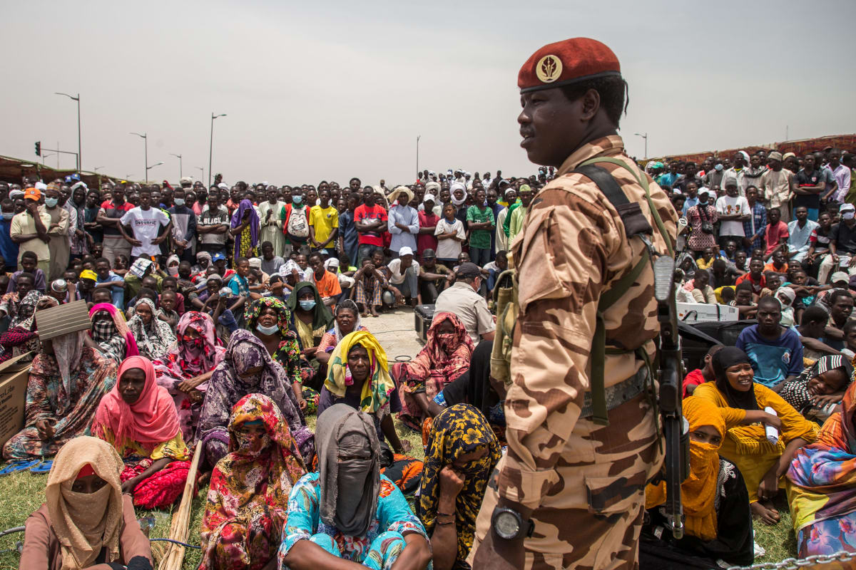 A soldier stands in front of a group of people. 