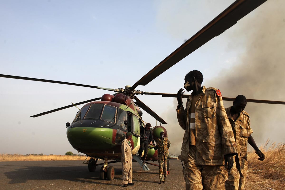 Sudan People’s Liberation Army (SPLA) soldiers and a journalist leave a helicopter after a flight to Bor, in Juba, South Sudan on January 25, 2014