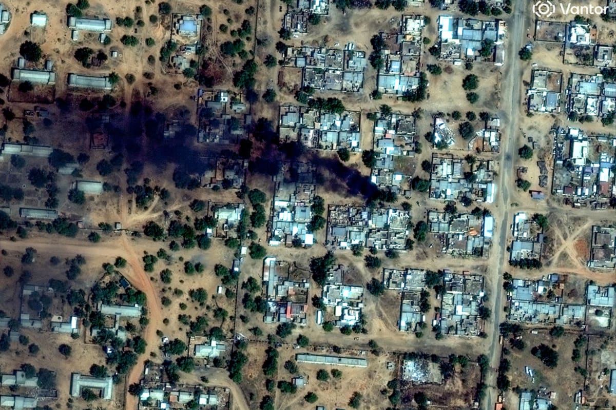 A satellite image shows smoke rising from a residential area.