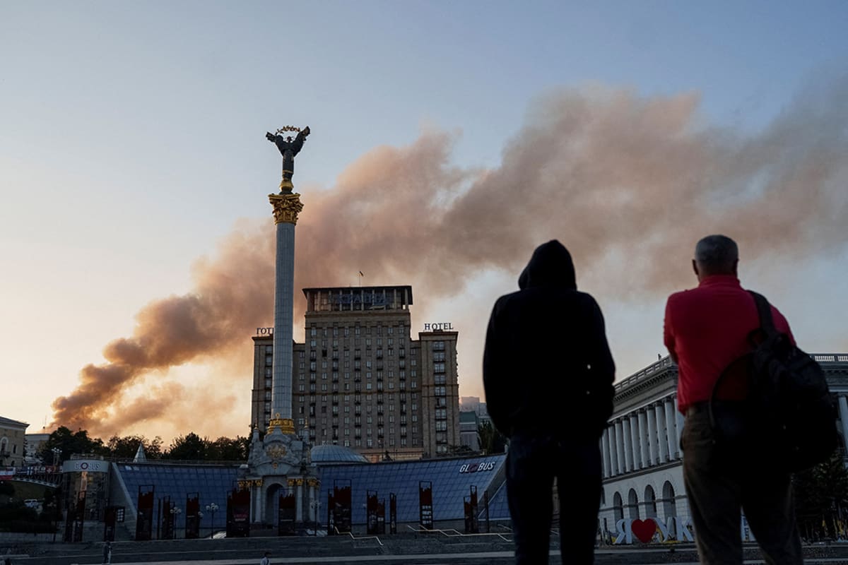 People look at smoke rise over a building.