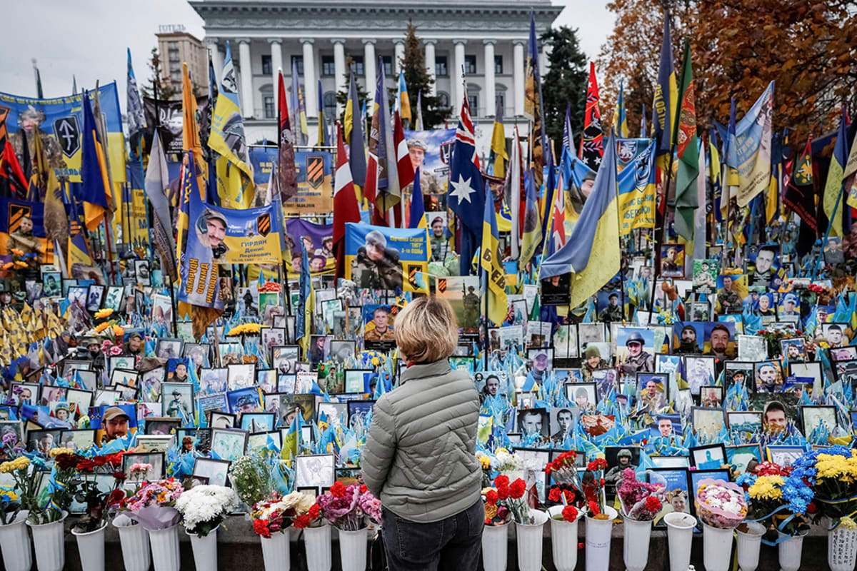A woman faces away from the camera while observing memorials to fallen soldiers.
