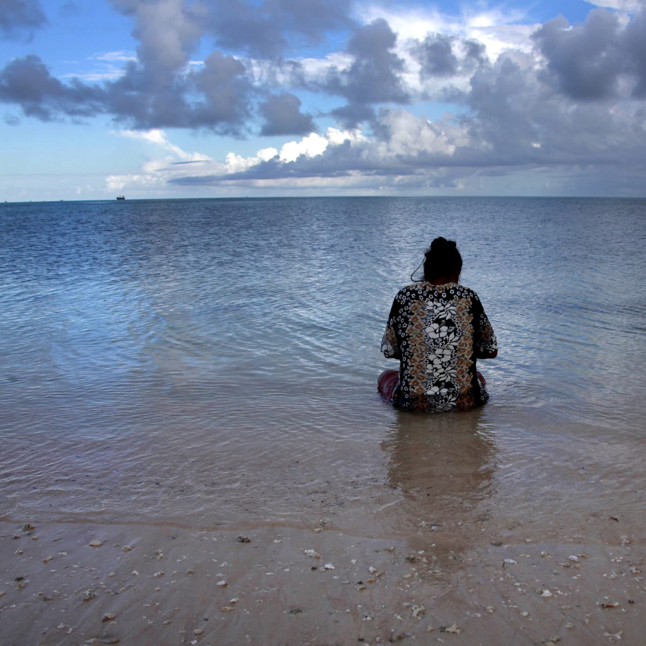 Binata Pinata scales a fish her husband caught, as she sits in the sea just off Bikeman islet, located off South Tarawa, in the central Pacific island nation of Kiribati, on May 25, 2013.