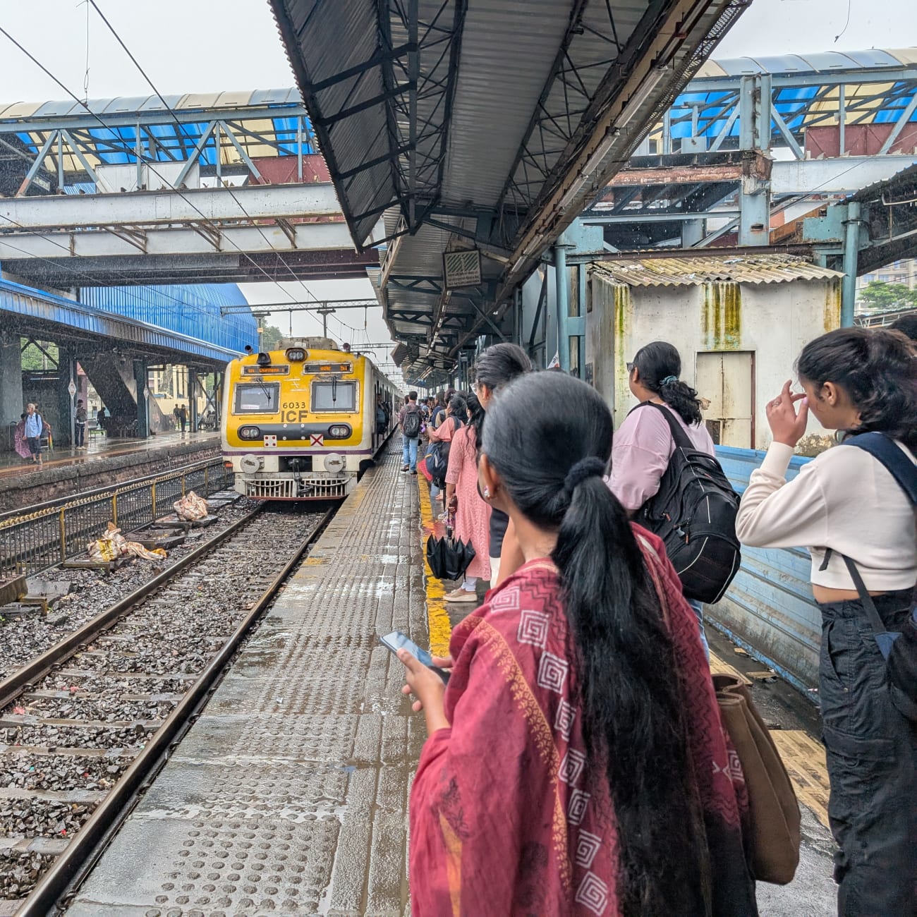 Commuters wait for a train at Goregaon railway station in suburban Mumbai on August 7, 2025.