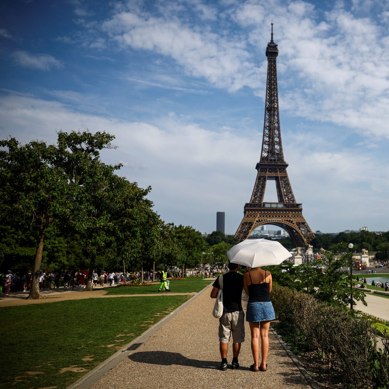 People protect themselves from the sun under an umbrella near the Eiffel Tower during a heatwave, in Paris, France, on June 20, 2026.