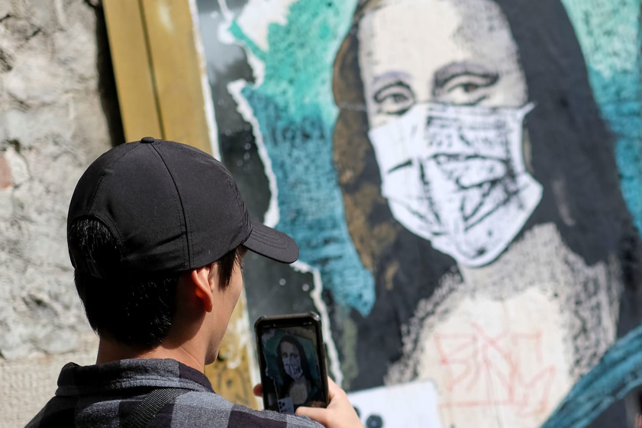 A tourist takes a picture of an image of Mona Lisa with a protective face mask after further cases of coronavirus were confirmed in Barcelona, Spain on March 6, 2020. The photo shows a man with dark hair and a black cap taking a cell phone photo of a likeness of Da Vinci's most famous painting with Mona wearing a mask. REUTERS/Nacho Doce
