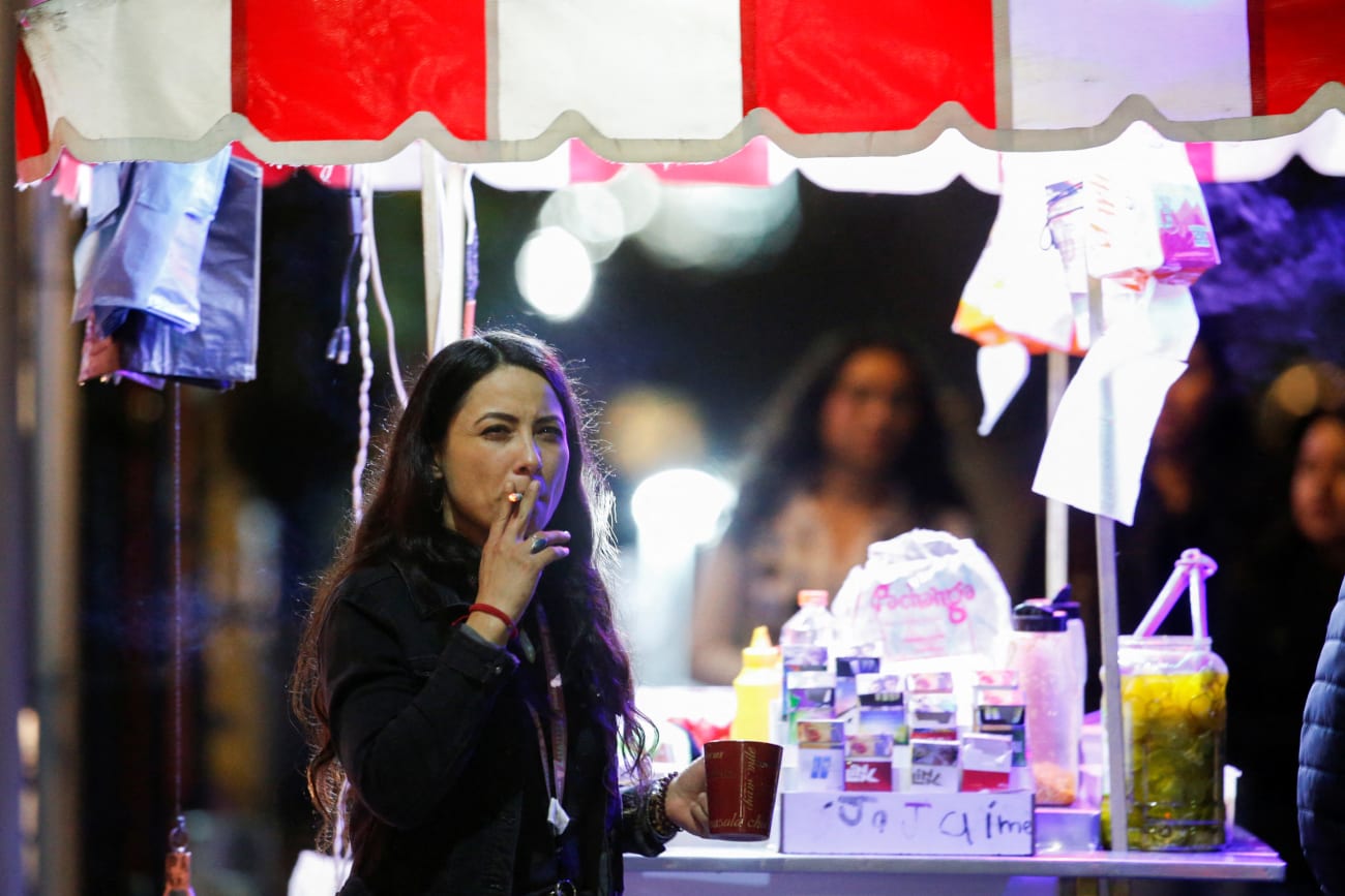 A woman smokes a cigarette next a food stall, before the Mexican government's regulation of the general law for tobacco control, in Monterrey, Mexico, on January 14, 2023.