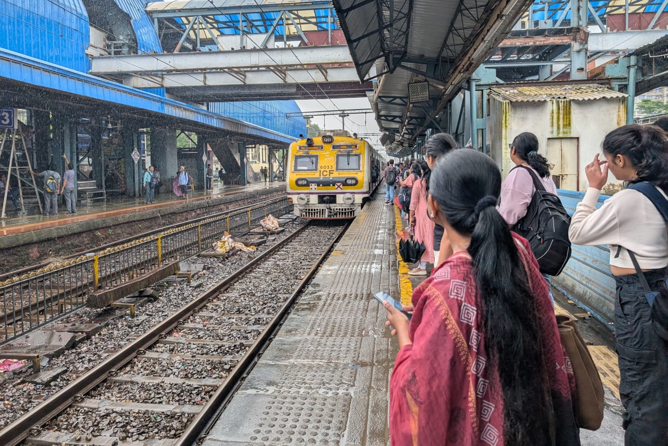 Commuters wait for a train at Goregaon railway station in suburban Mumbai on August 7, 2025.
