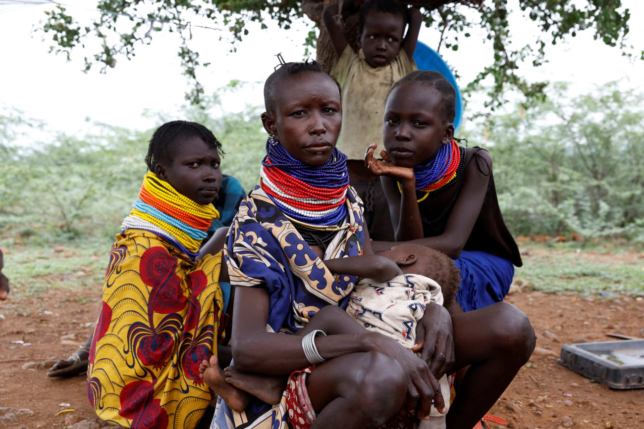 Turkana women sit under a tree as community health workers screen their children for malnutrition, in Aposta village, Turkana County, Kenya, on October 30, 2025.