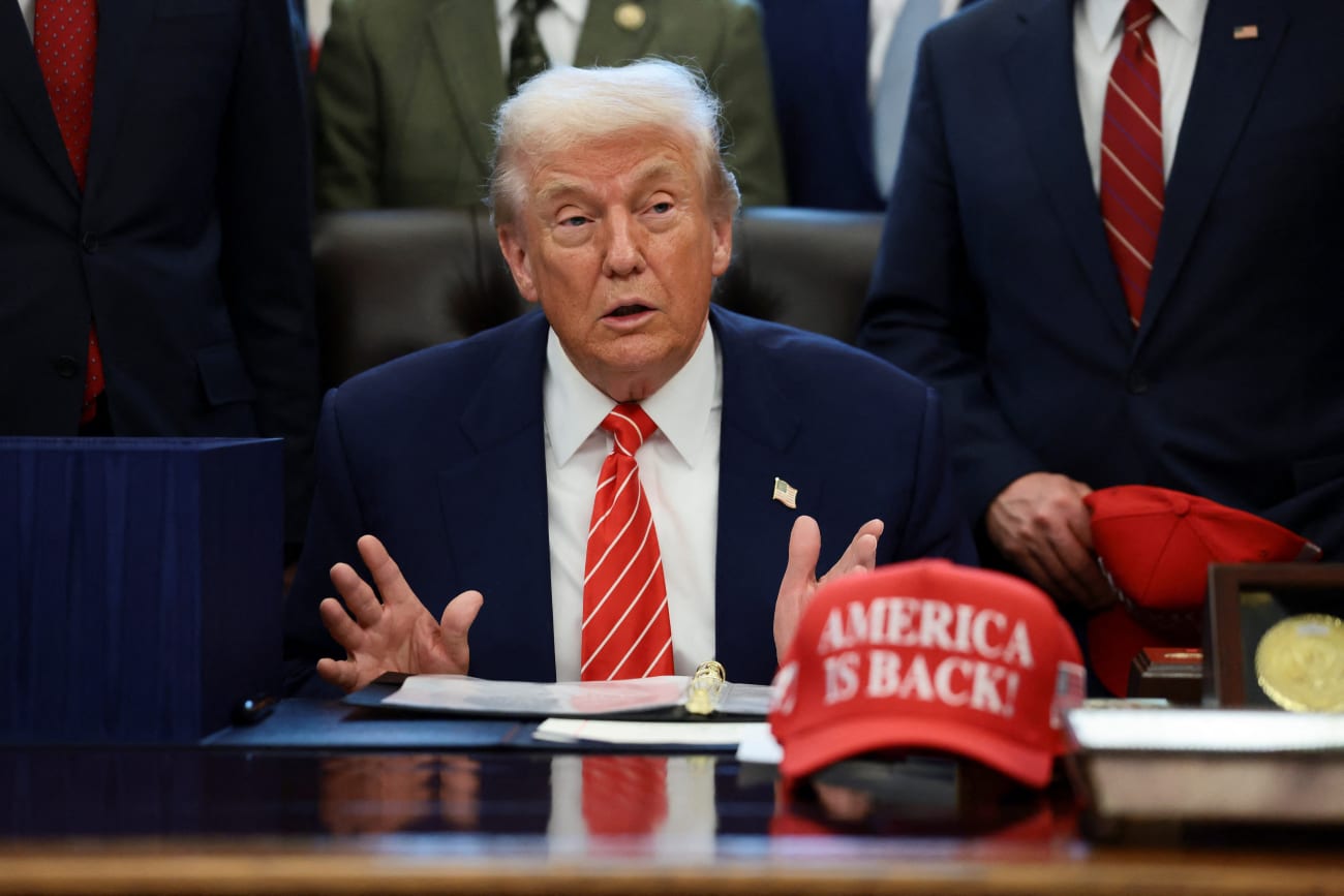 U.S. President Donald Trump sits at his desk, behind a hat that reads "America is back" at the White House, in Washington, DC, on February 3, 2026.