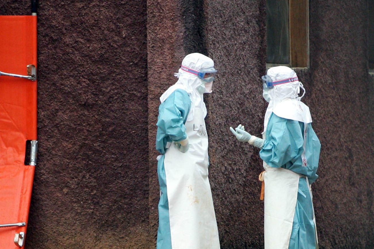 Health workers in protective clothing confer behind barriers marking the isolation ward where victims Marburg virus are treated, in Uige, Angola, on April 20, 2005.
