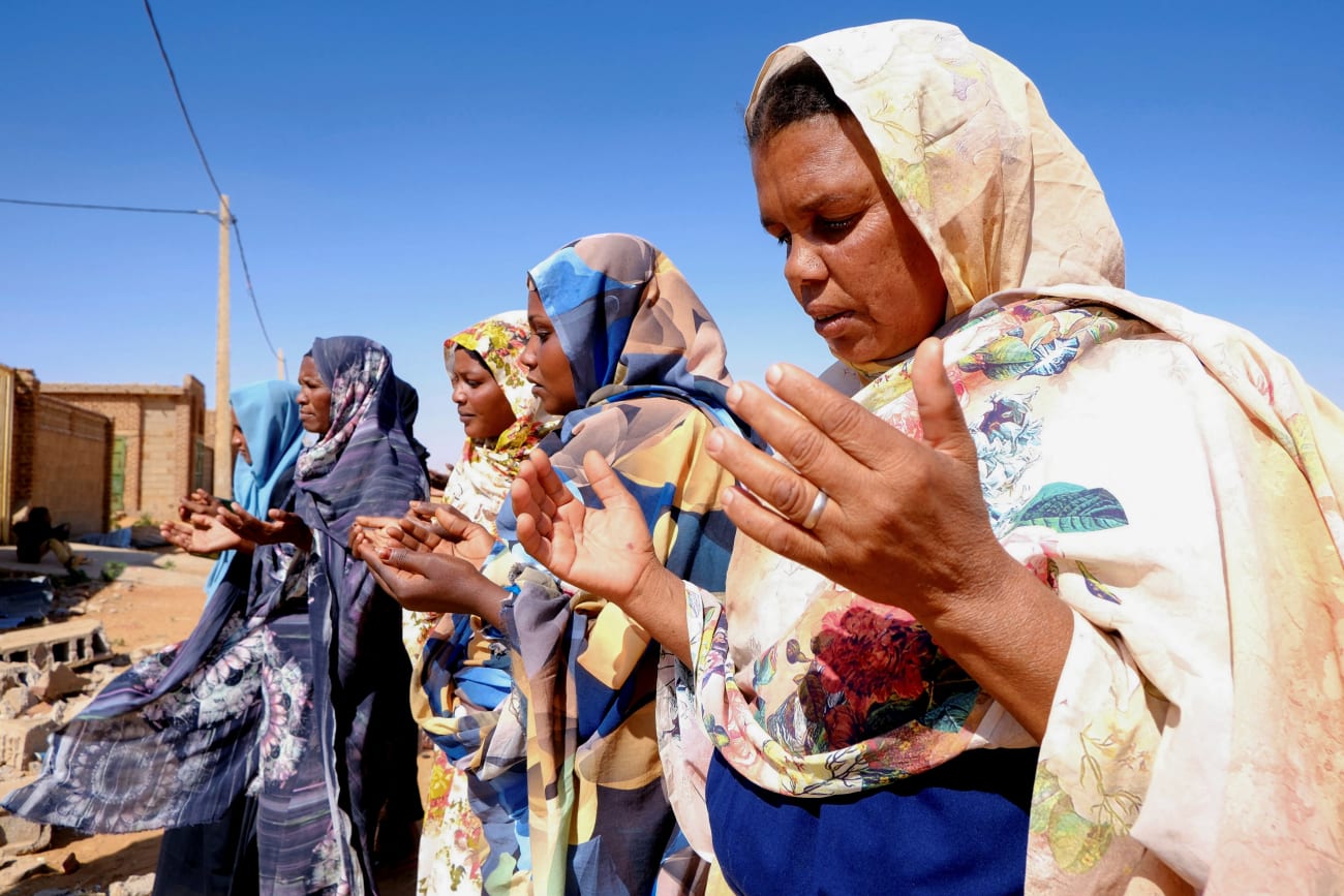 Women pray in front of a house struck by a drone in El-Obeid, North Kordofan State, Sudan, on January 12, 2026.