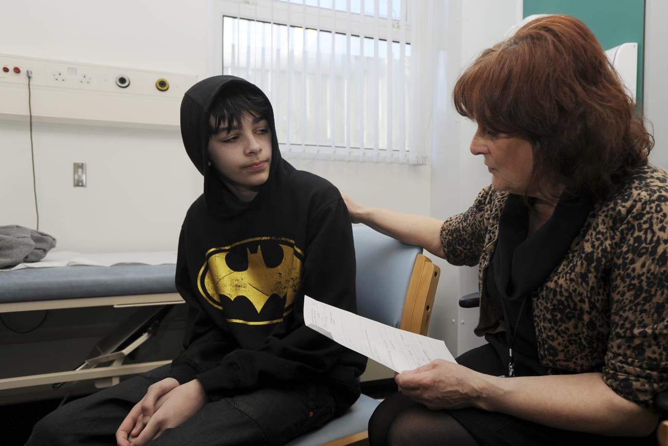 School Nurse Carolyn Rees talks to Kieran Elford, aged 13, about the MMR vaccine at the pediatric outpatients department at Morriston Hospital, in Swansea, south Wales, on April 6, 2013.