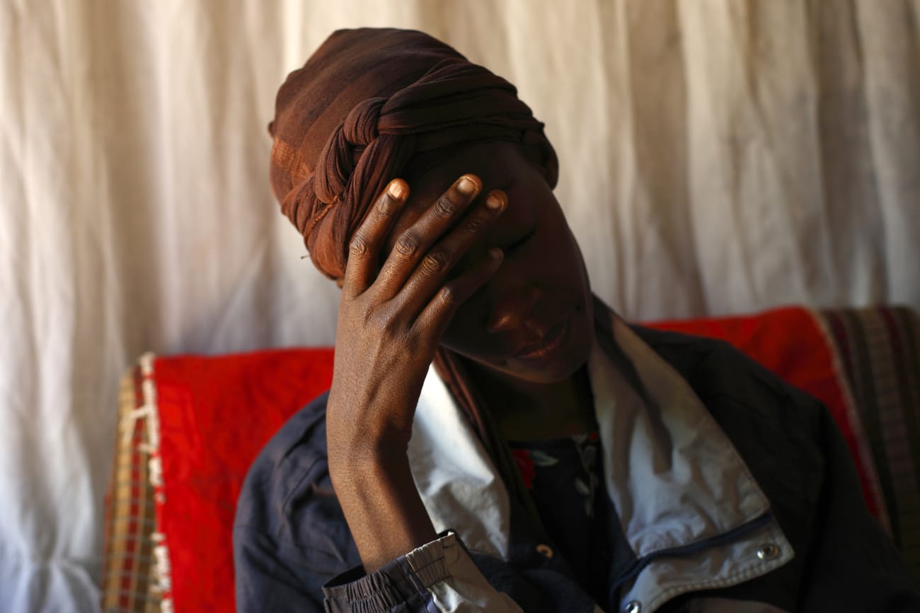 An HIV patient places her hand on her forehead during a visit by a caregiver at her home, in Lusaka, Zambia, on April 17, 2012.