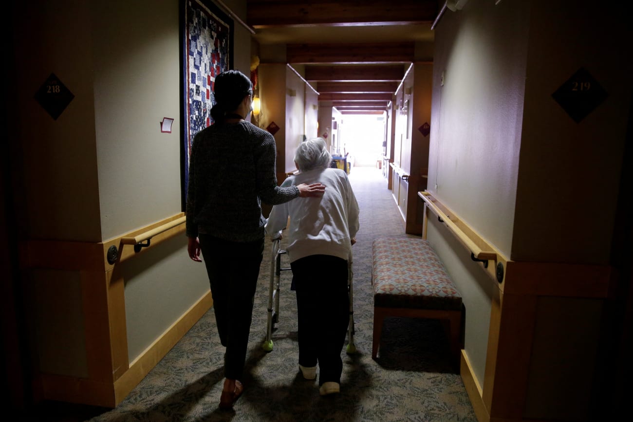 An elderly woman is guided back to her room for a family visit at Nikkei Manor, an assisted living facility, in Seattle, Washington, on March 30, 2021.