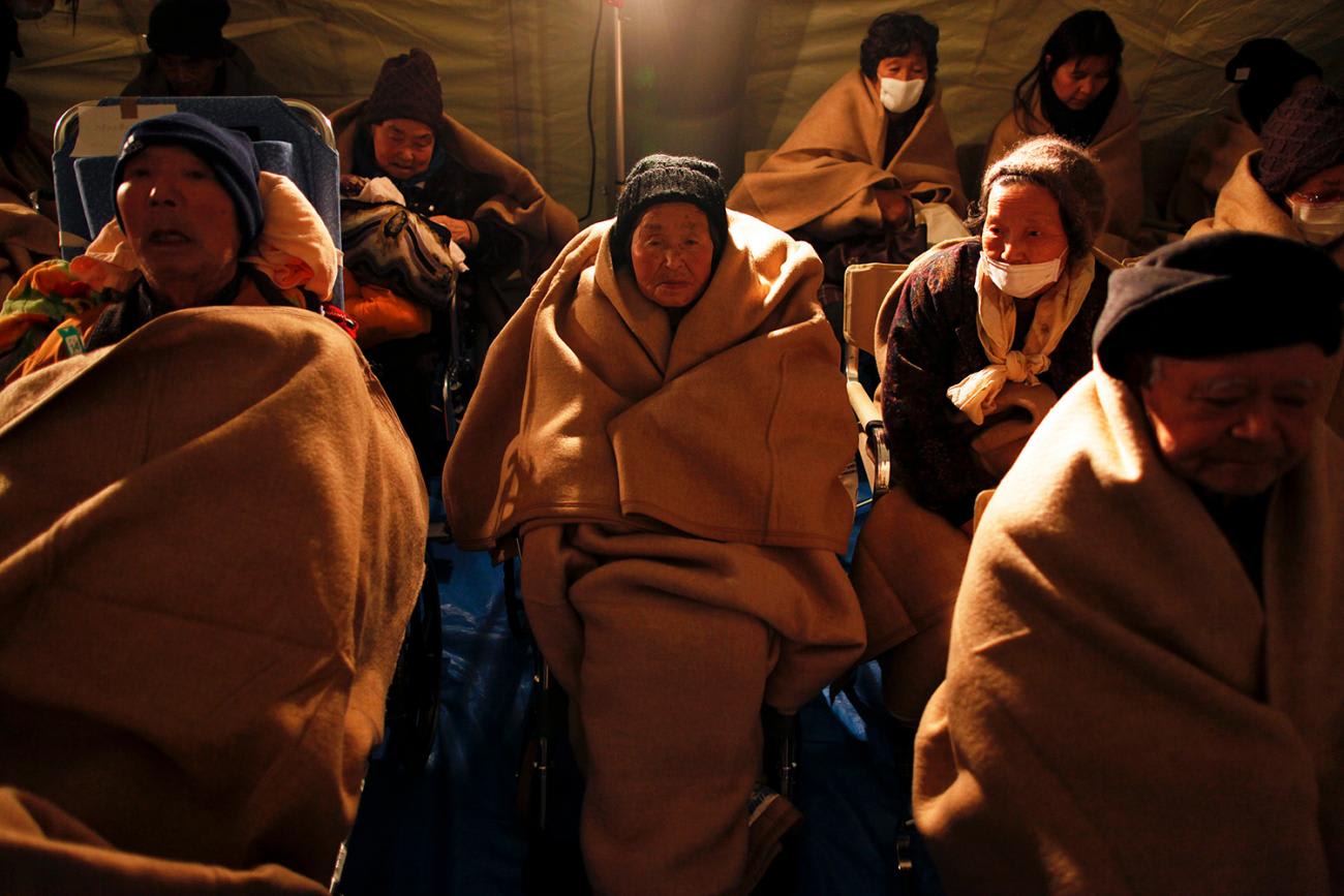 Photo shows a half dozen people all wrapping themselves in generously sized fluffy brown blankets.