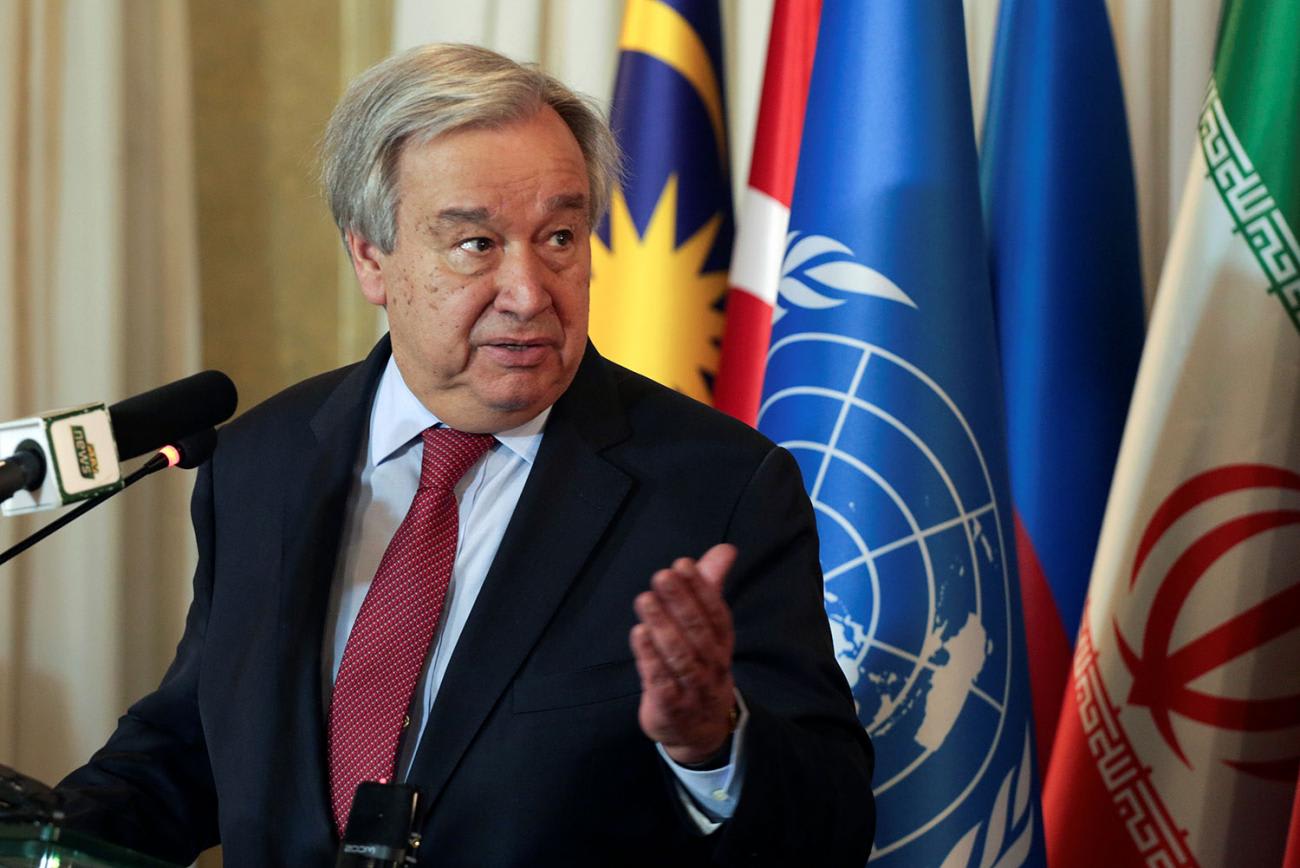 The photo shows the Secretary-General standing at a podium speaking into a microphone.