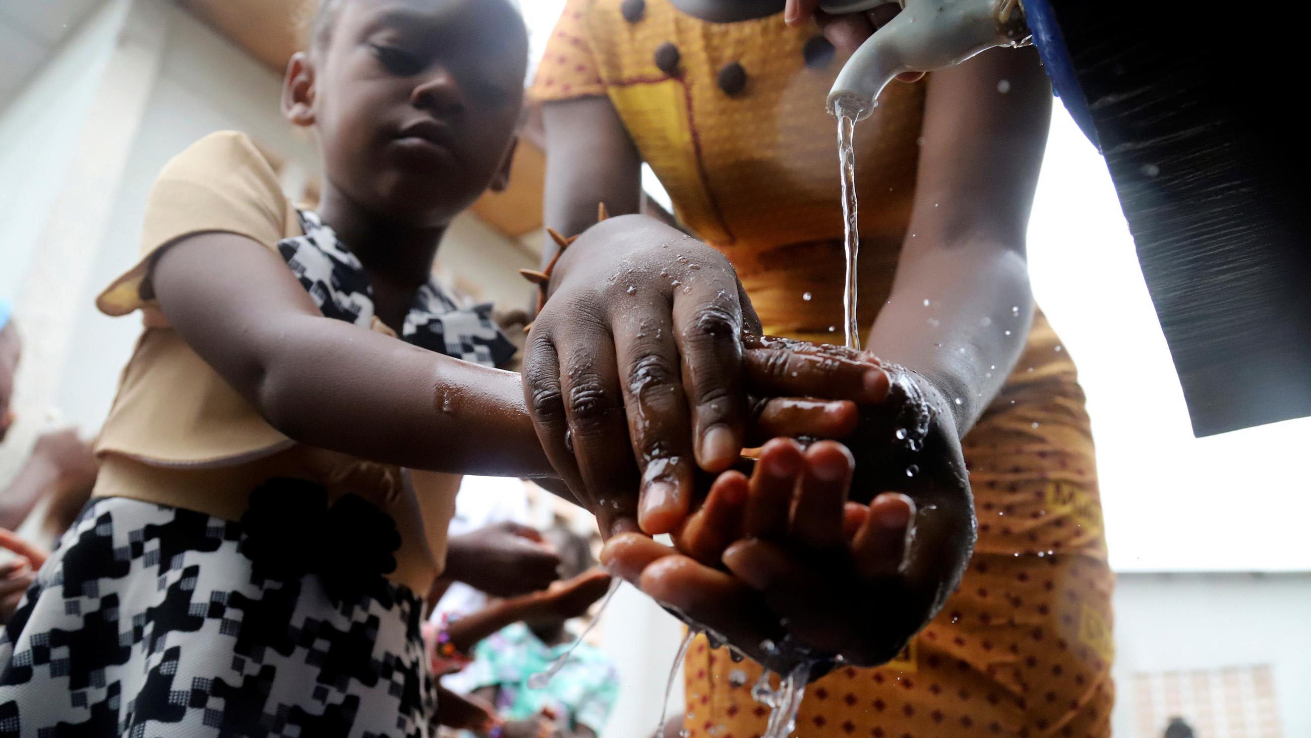 The photo shows a grown-up helping the child wash.
