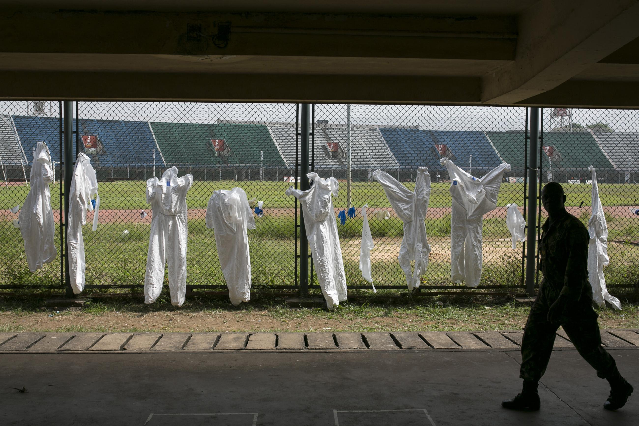 A Sierra Leonean soldier walks pest protective clothing drying on a fence, in the Ebola Training Academy, in Freetown, Sierra Leone, on December 16, 2014.