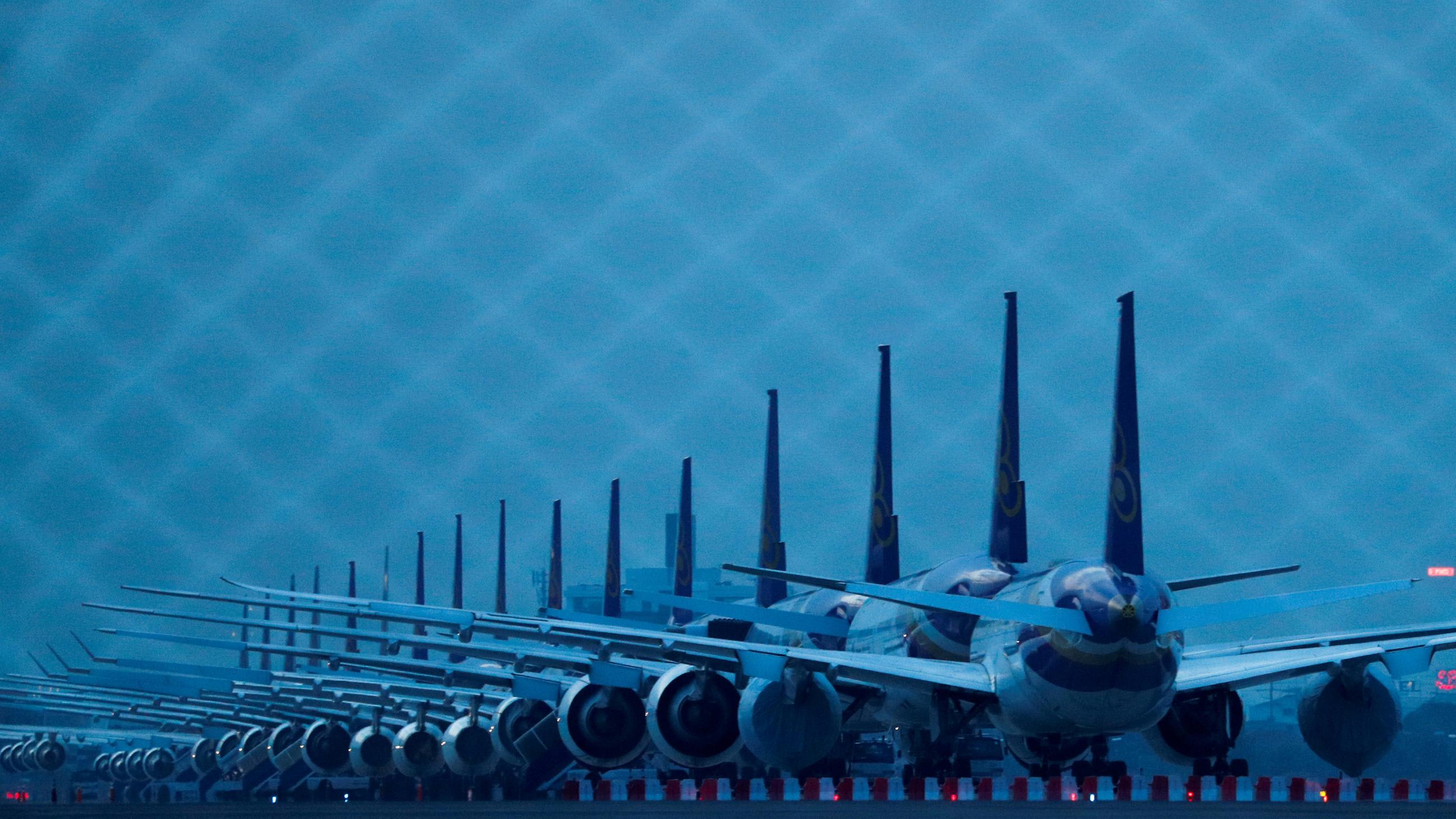 The photo shows a row of airplanes at dusk in a dark blue light.