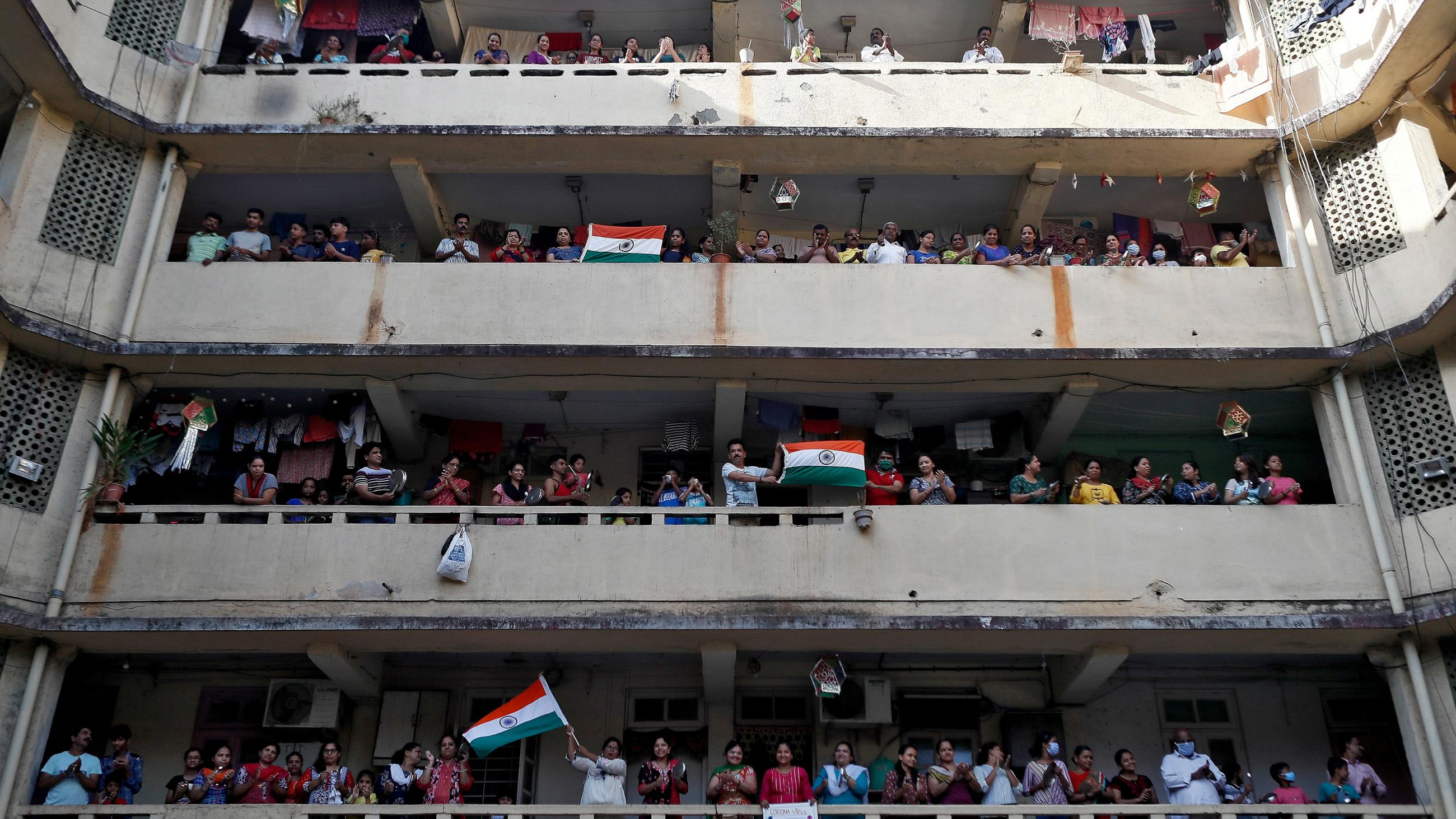 The photo shows three balconies of a large building filled with people cheering.