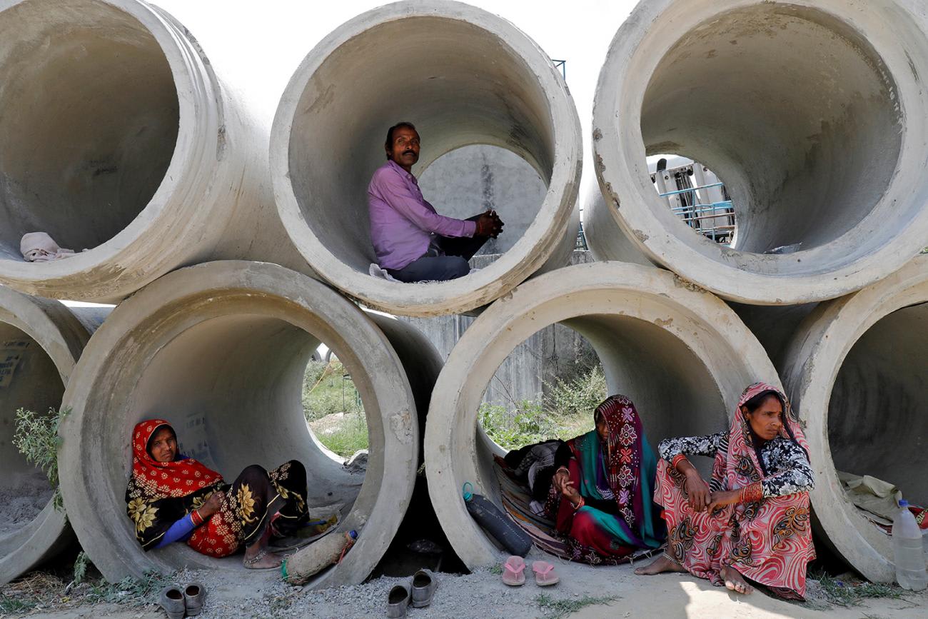 This is a powerful image of people inside stacked cement pipes of large enough diameter for them to camp out in.