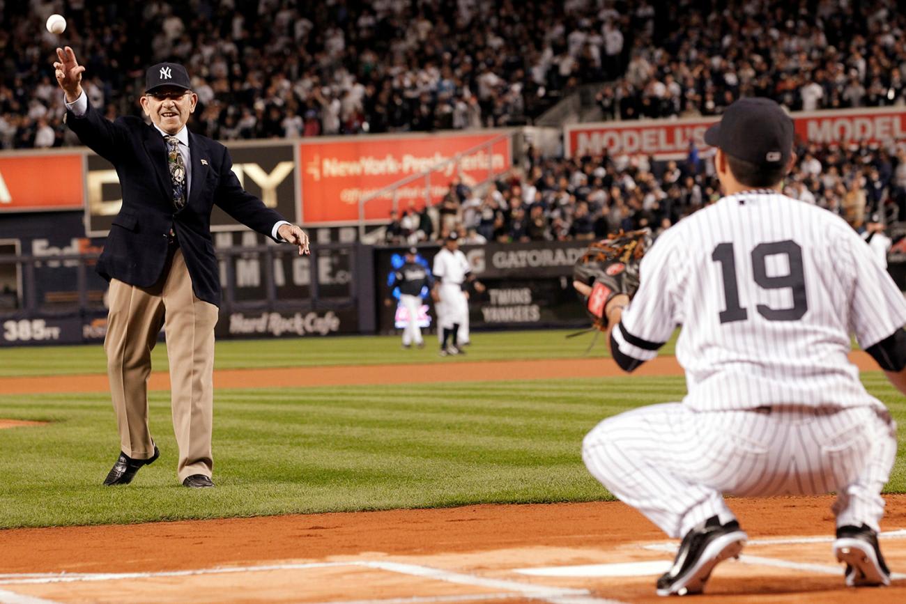 The photo shows an elderly Berra with a big grin throwing the ball to the plate.