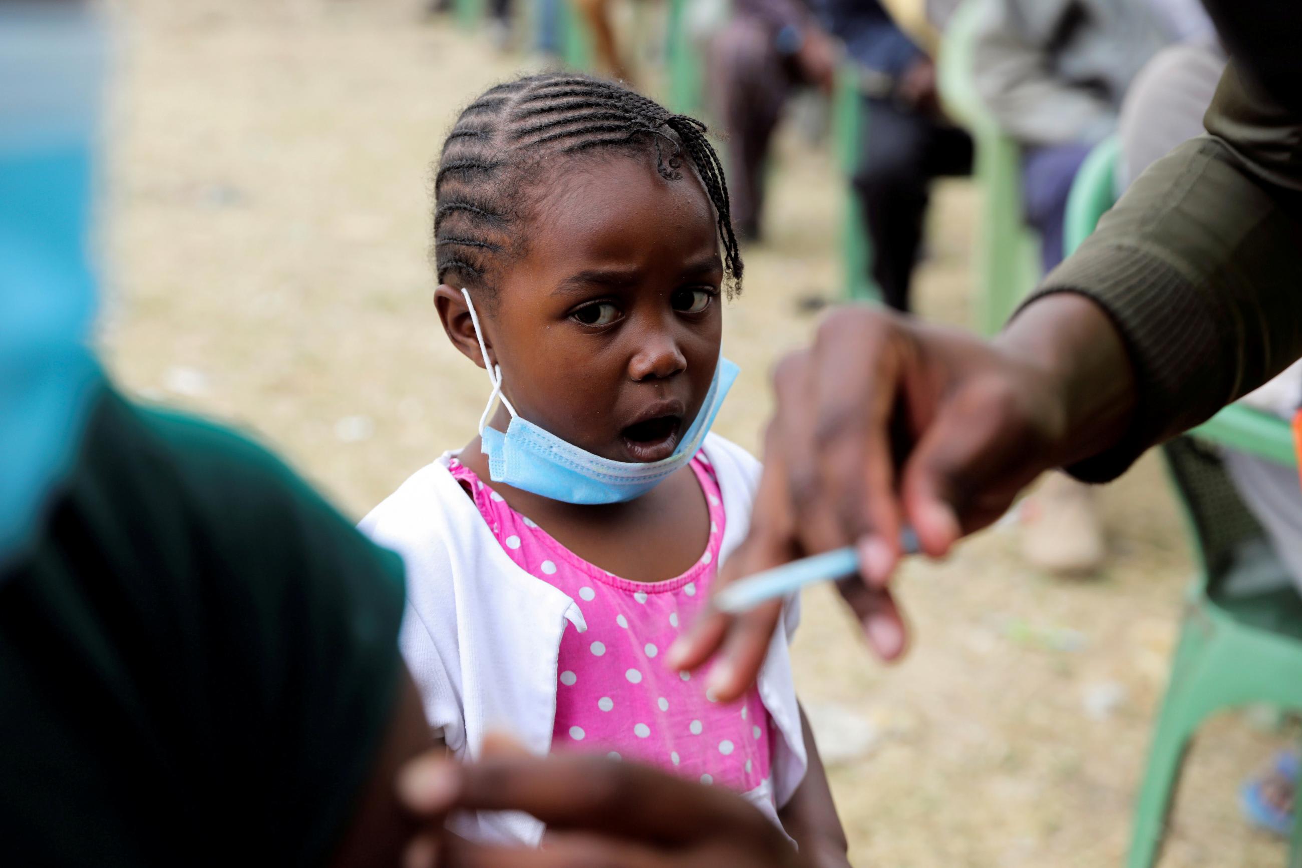 A girl reacts as her father receives an AstraZeneca/Oxford COVID-19 vaccine, donated to Kenya by the UK government, in Nairobi, Kenya, on August 8, 2021.